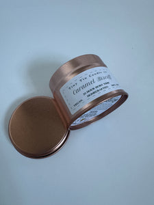 homemade candle labeled 'Caramel Biscoff' by Tiny Tin Candle with a 23-hour burn time, advertised as vegan and handcrafted. side and bottom of candle