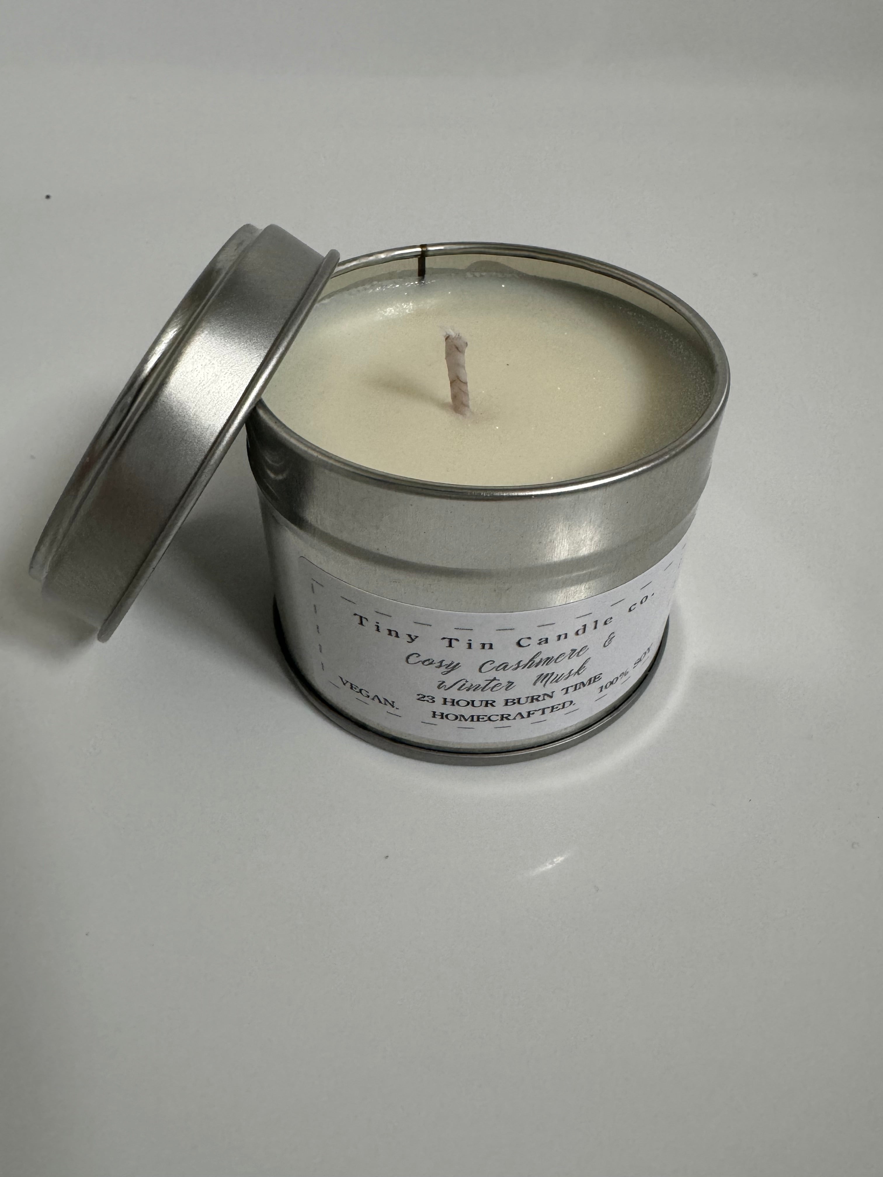 Homemade Candle Cosy Cashmere & Winter Musk 100ml Soy Tin Candle . top and front of candle with lid balancing next to candle