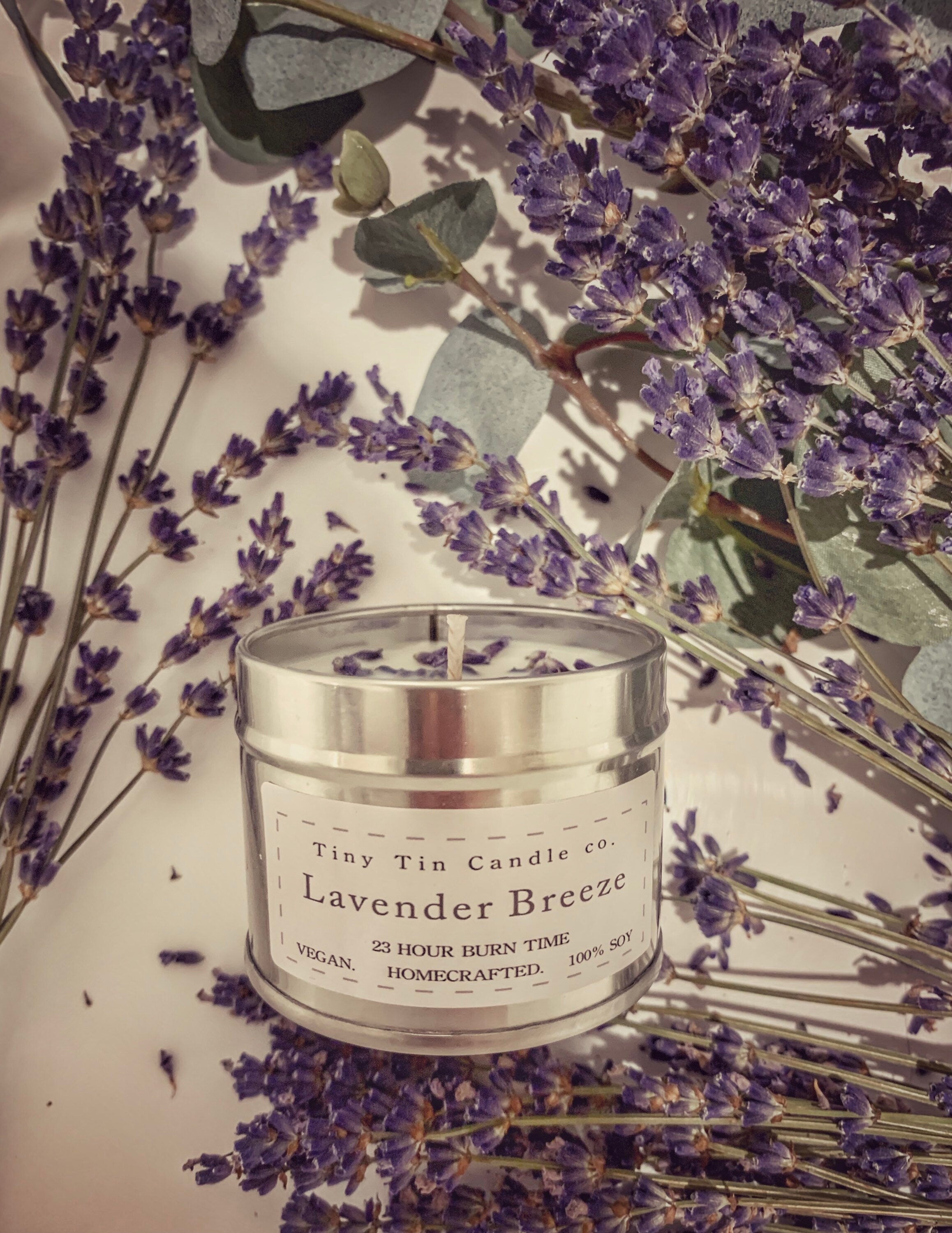 A homemade candle  Lavender Breeze scented candle from Tiny Tin Candle Co., displayed among fresh lavender sprigs, highlighting the natural, artisanal essence of the soy candle