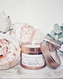 A homemade Candle Peony & Blush scented candle from Tiny Tin Candle Co., presented with delicate peony flowers, capturing a sophisticated and artisanal ambiance